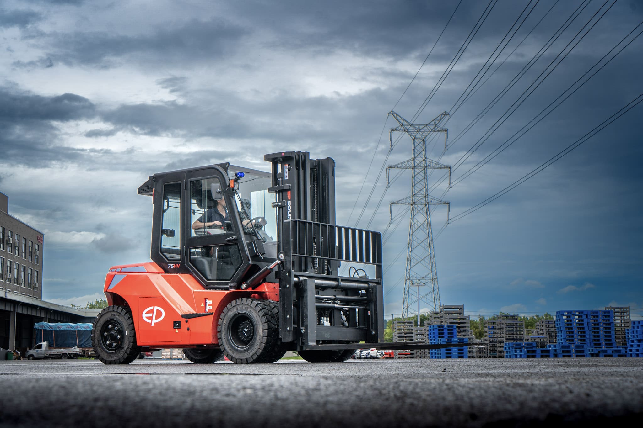 Electric forklift lifting timber bundle in yard