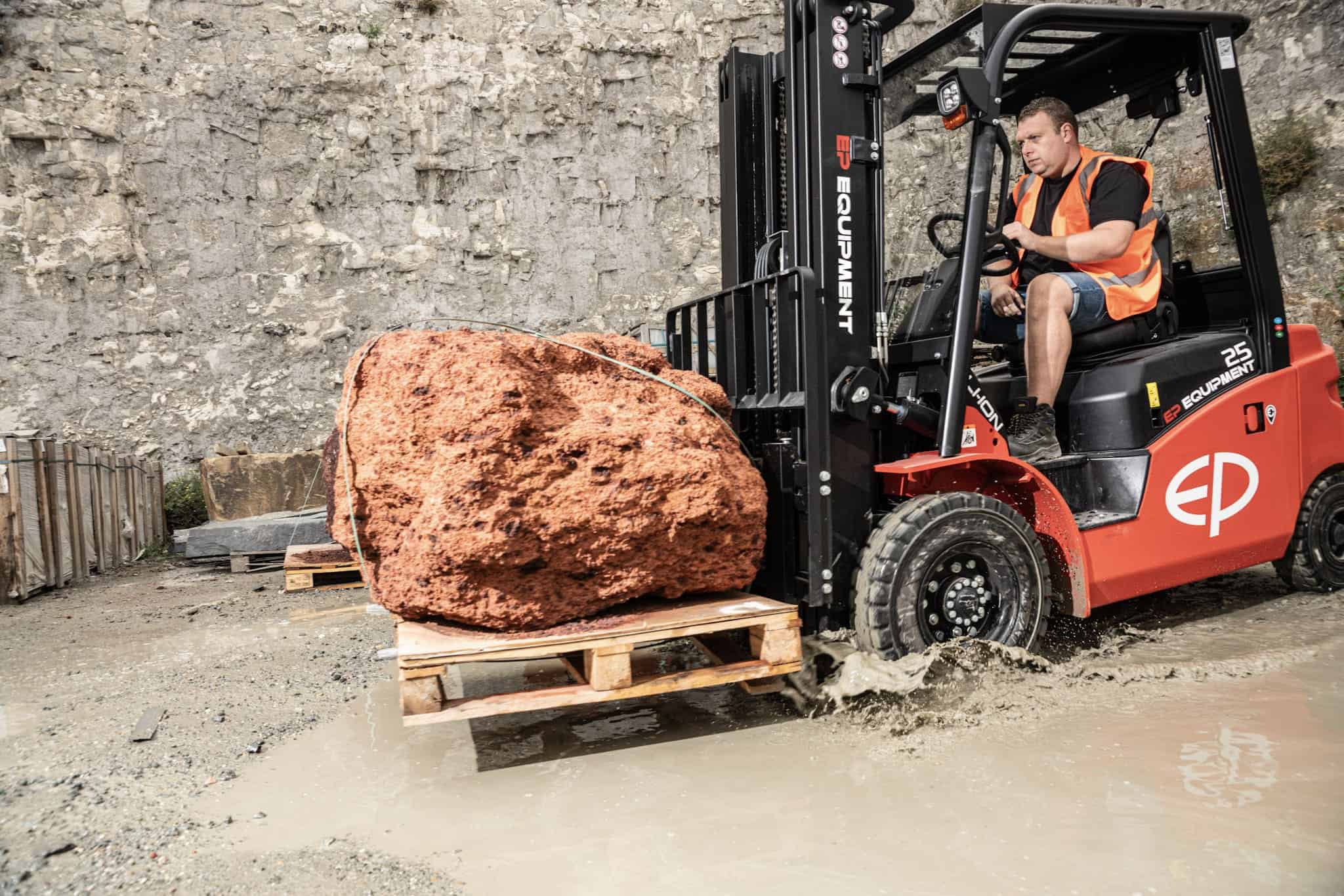 Electric forklift lifting timber bundle in yard