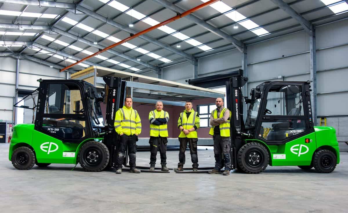 Four members of the Clearlift team in hi-vis between two green EP electric forklifts