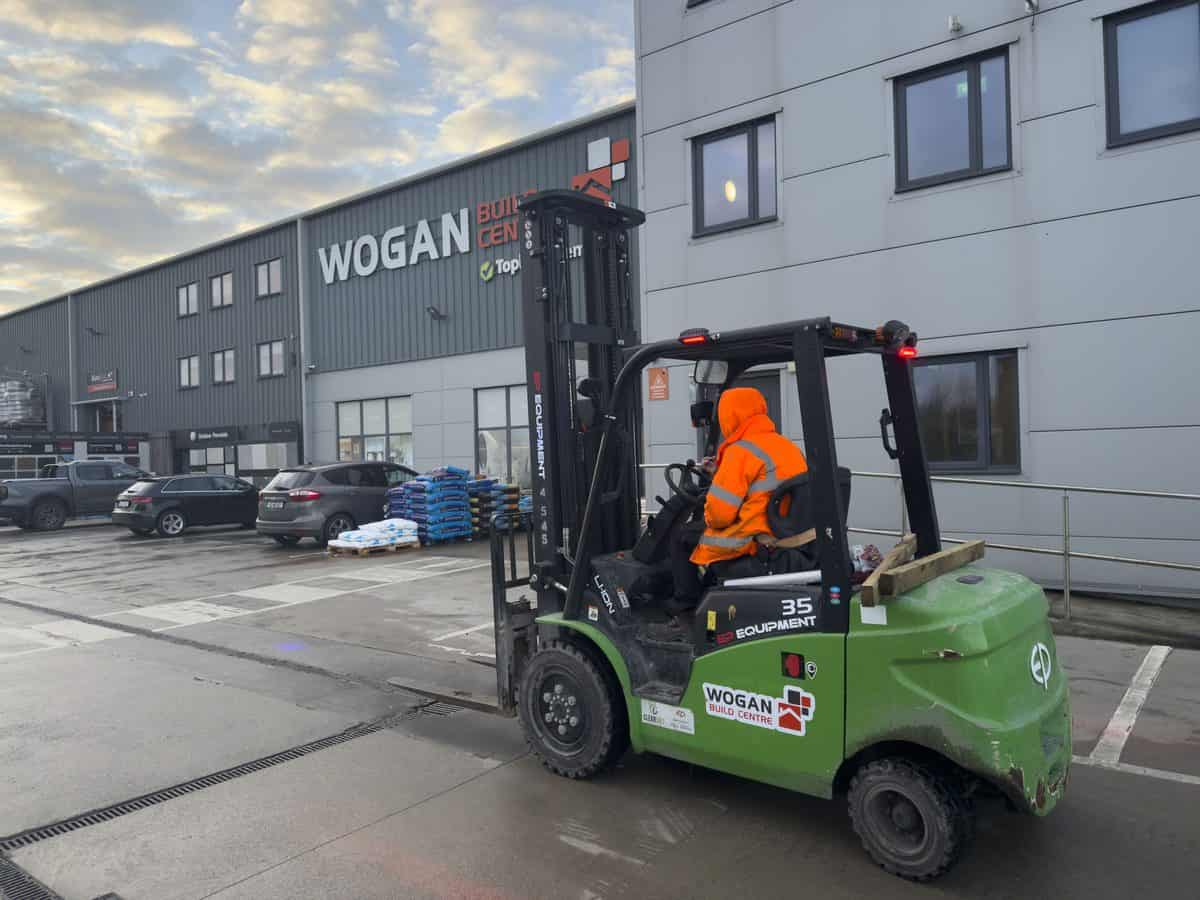 Driver in hi-vis on a green EP 35 lithium-ion forklift in a build centre car park