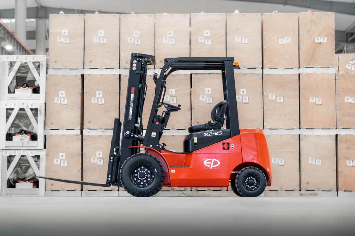 EP X2 4-wheel electric forklift side view in front of stacked crates