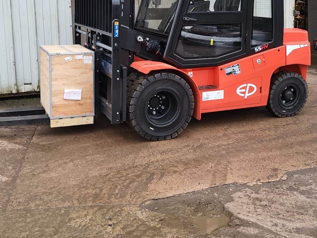 EP 55HV heavy-duty electric cab forklift lifting a crate in a manufacturer's yard