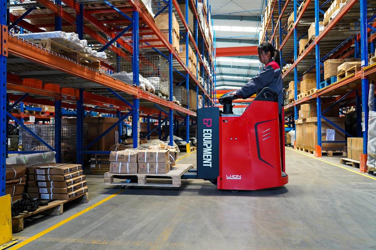 Operator driving an EP lithium rider pallet truck through a warehouse
