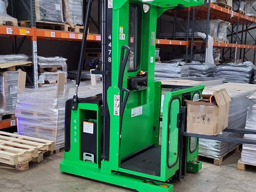 Green EP order picker in a wholesale warehouse aisle with boxed stock